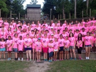 Group of campers wearing pink t-shirts standing in an amphitheater.