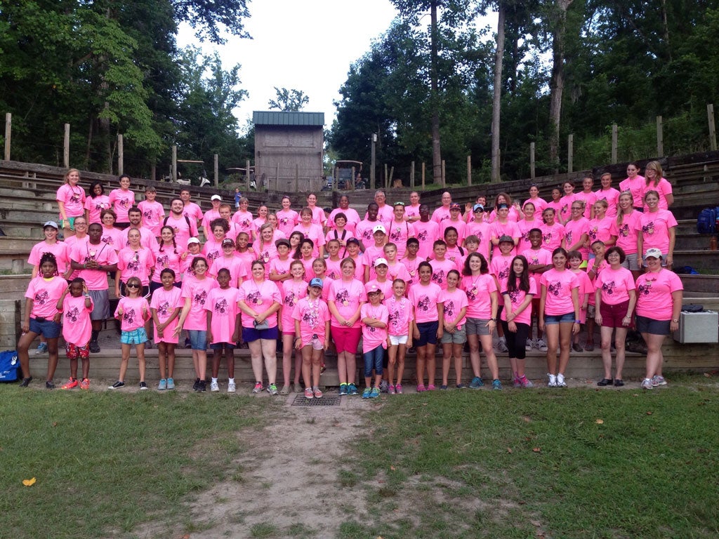 Group of campers wearing pink t-shirts standing in an amphitheater.