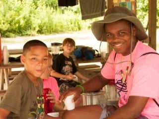 A young male camper and an adolescent male smile for the camera.