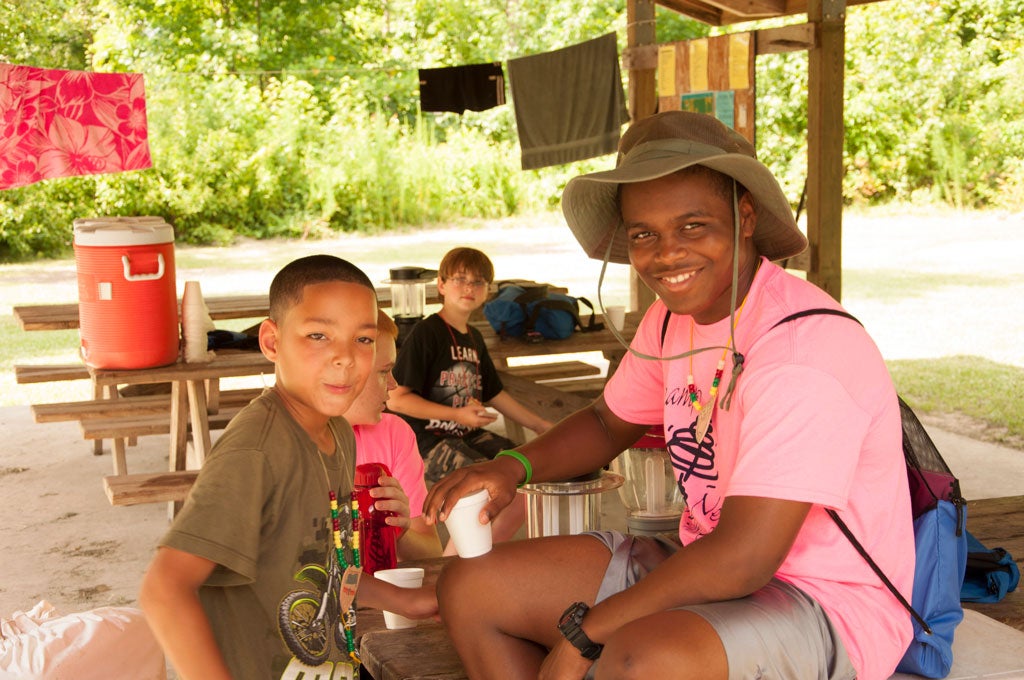 A young male camper and an adolescent male smile for the camera.