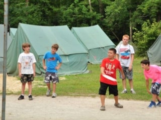 A group of young male campers playing with a frisbee.