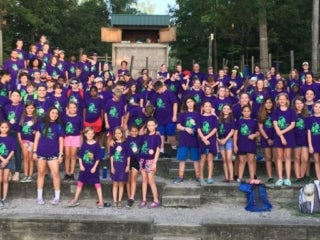 A group of campers wearing purple t-shirts standing in an amphitheater.