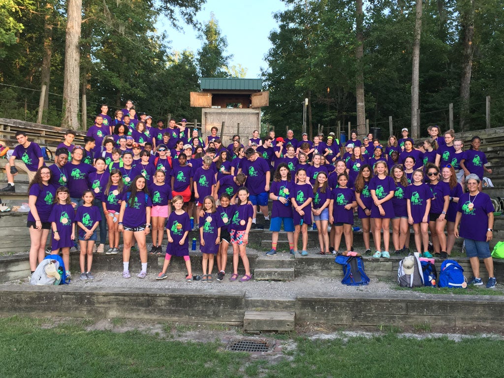 A group of campers wearing purple t-shirts standing in an amphitheater.