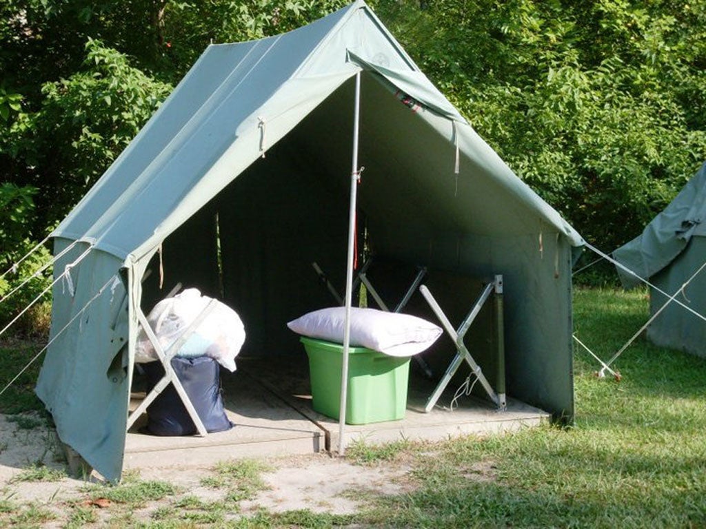 A green tent with a plastic tub, pillow, and a couple bags inside.