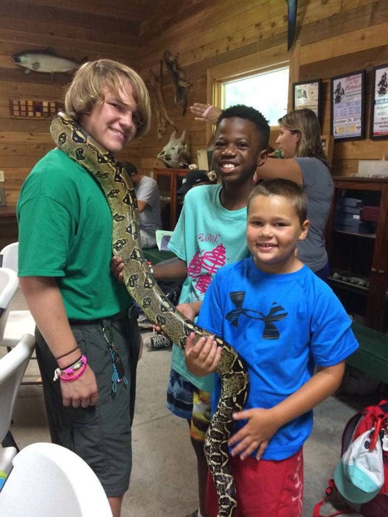 Three campers hold a large snake.