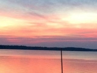 Colorful sunset over a body of water. The clouds are pink, purple, and gold against a blue sky.