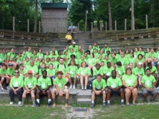 Group of campers in bright green t-shirts sitting in an amphitheater.