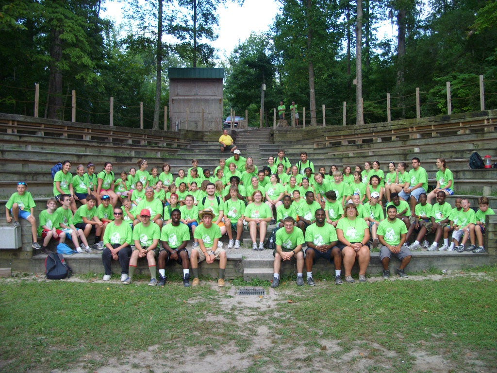 Group of campers in bright green t-shirts sitting in an amphitheater.
