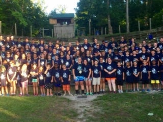 A group of campers wearing navy t-shirts standing in an amphitheater.