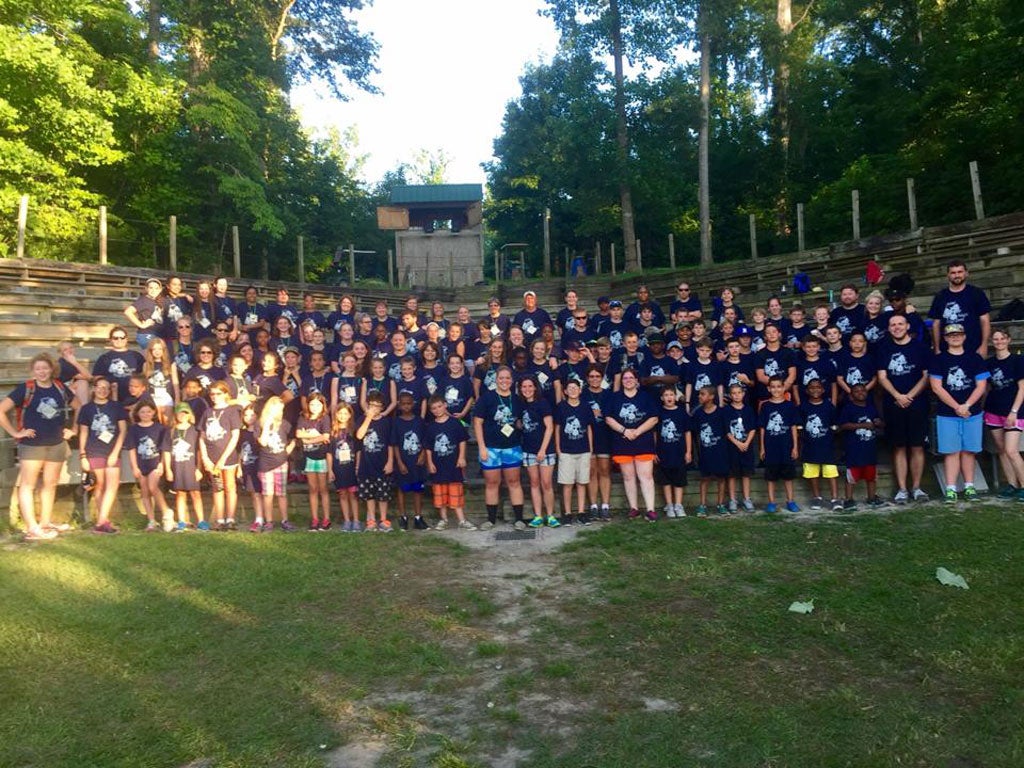 A group of campers wearing navy t-shirts standing in an amphitheater.